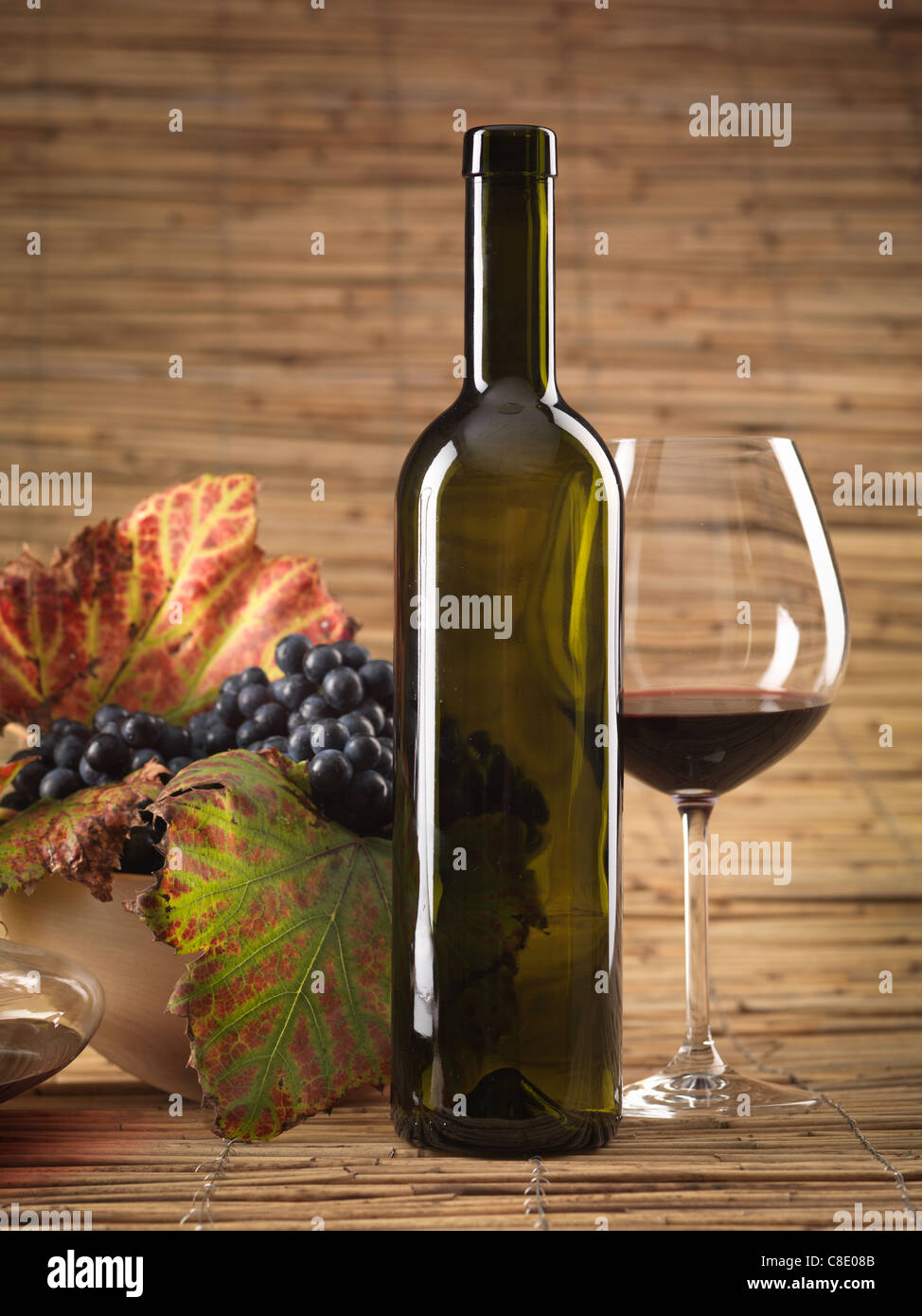 Bouteille de vin rouge, verre, raisins sur fond d'osier Banque D'Images
