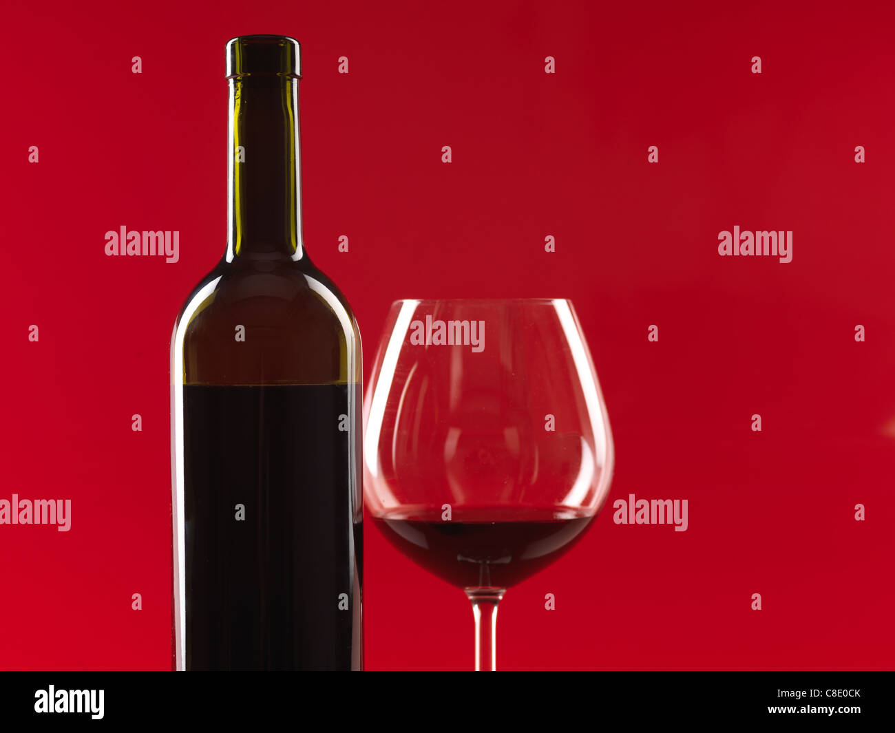 Détail de bouteille de vin et le verre de vin rouge, sur fond rouge, copy space Banque D'Images