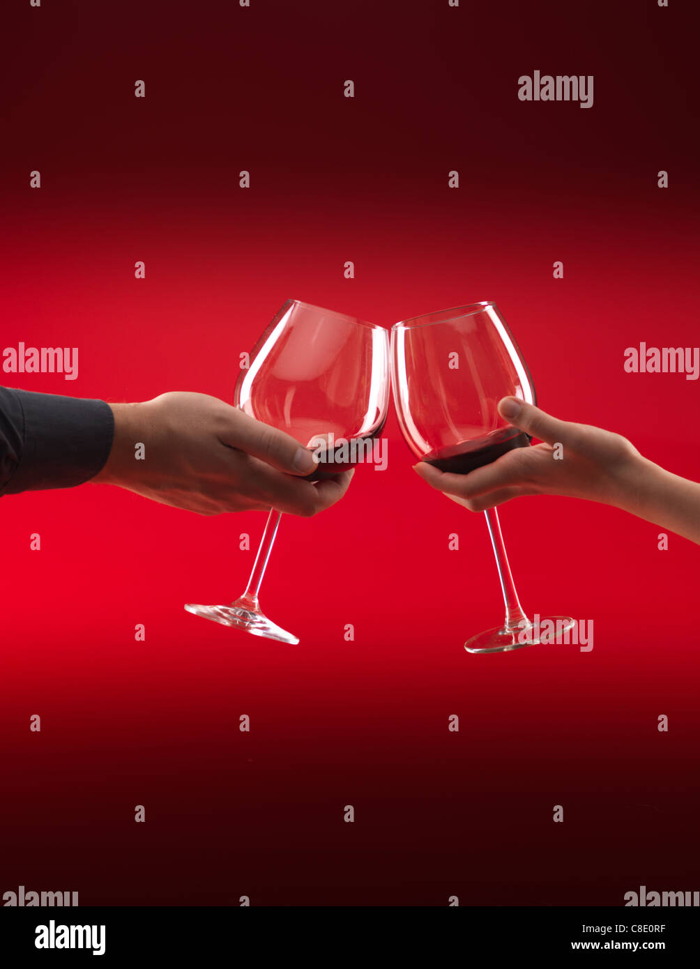 Les mains de l'homme et de la femme tenant des verres de vin rouge, grillage, sur fond rouge Banque D'Images