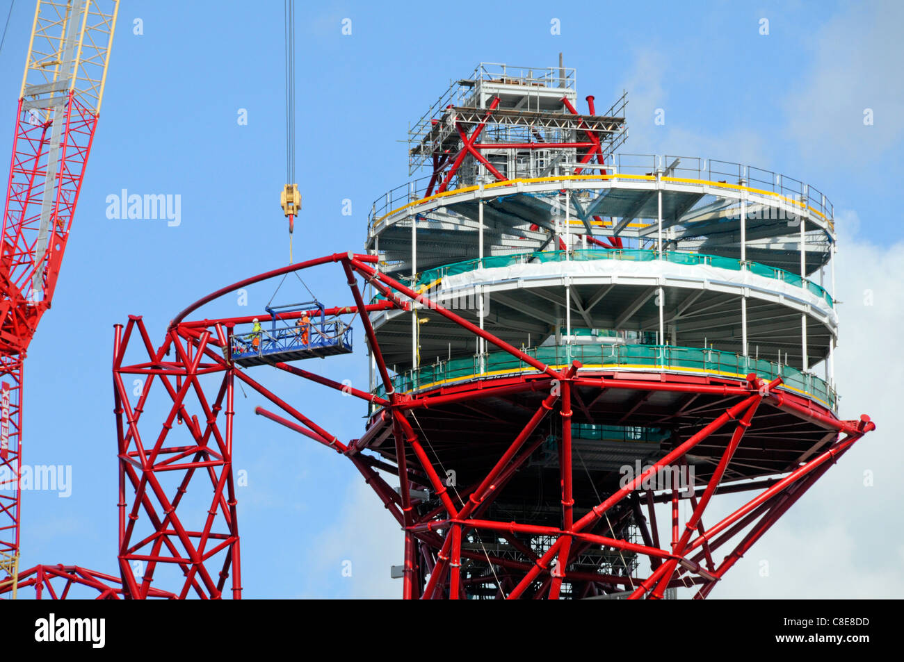 Une plate-forme de la grue prend en charge les travailleurs à côté des tubes d'acier autour de la plate-forme d'observation incomplète haut de ArcelorMittal Orbit tour pour Jeux Olympiques de 2012 à Londres UK Banque D'Images
