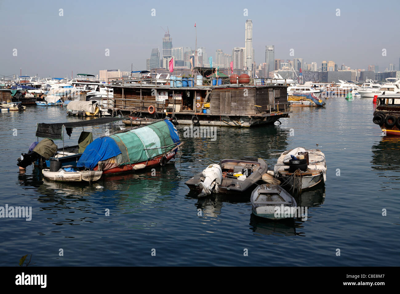 Pêche et bateaux maison délabrée à Hong Kong's Victoria Harbour, avec des gratte-ciel à l'horizon derrière, Hong Kong, Chine Banque D'Images