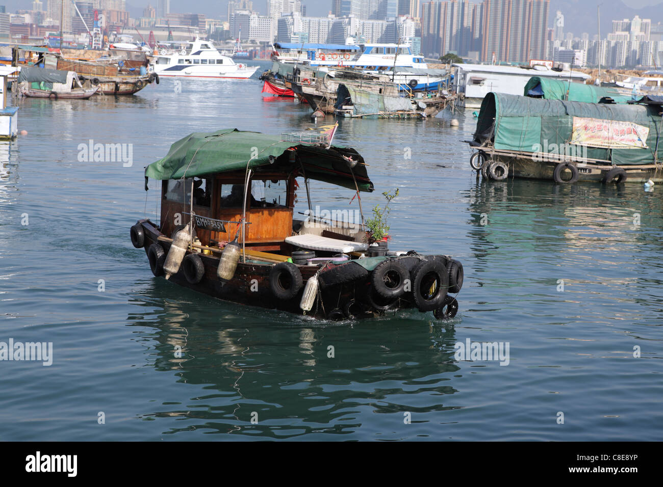 Ramshackle bateaux de pêche dans le port de Victoria de Hong Kong, avec des toits de la ville derrière, Chine Banque D'Images