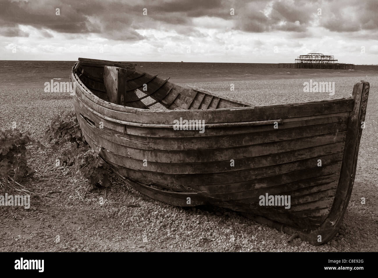 Photo en noir et blanc d'un bateau sur la plage de Brighton avec le Burnt Out West Pier dans l'arrière-plan Banque D'Images