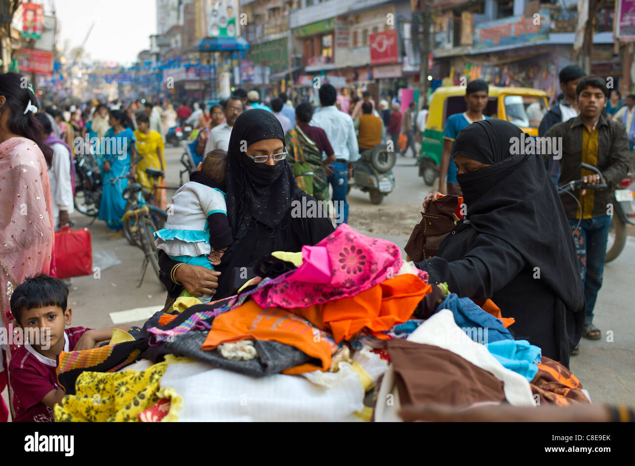 Scène de rue dans la ville sainte de Varanasi, les jeunes femmes musulmanes en burkhas noir shopping avec leurs enfants, Benares, Inde du Nord Banque D'Images