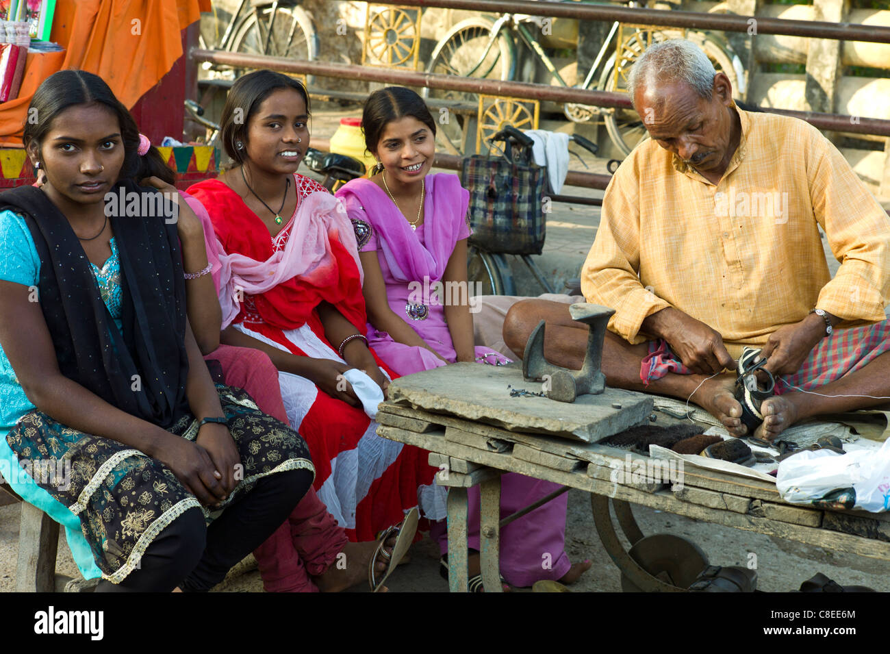 Les filles indiennes en magasin de chaussures avec cordonnier au travail à Sarnath, près de Varanasi, Benares, Inde du Nord Banque D'Images