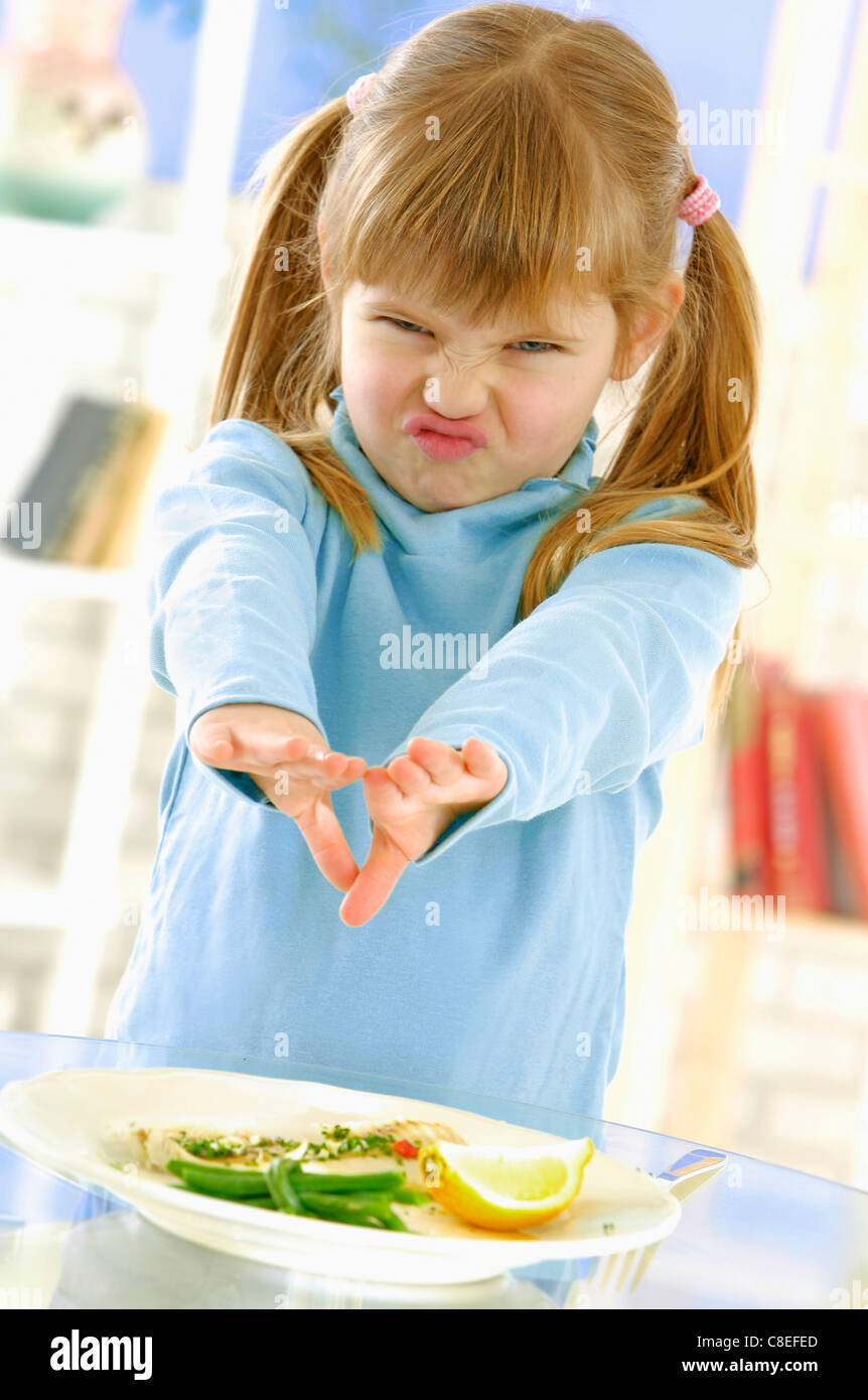 Jeune fille faisant un visage devant une assiette de poisson Banque D'Images