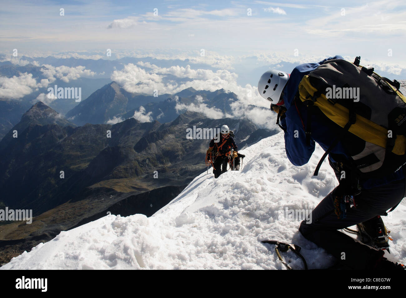 Un photographe à prendre des photos que d'une équipe de grimpeurs atteindre le sommet d'un pic dans les alpes Banque D'Images