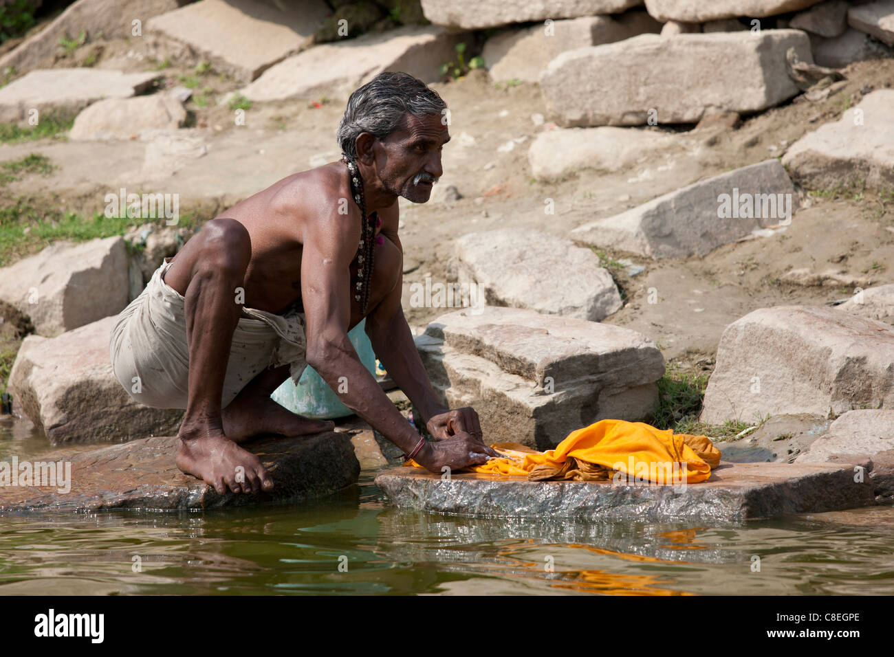 Laver les vêtements indiens en fleuve Ganges en utilisant la méthode traditionnelle à Kali Ghat de Varanasi, Inde Banque D'Images