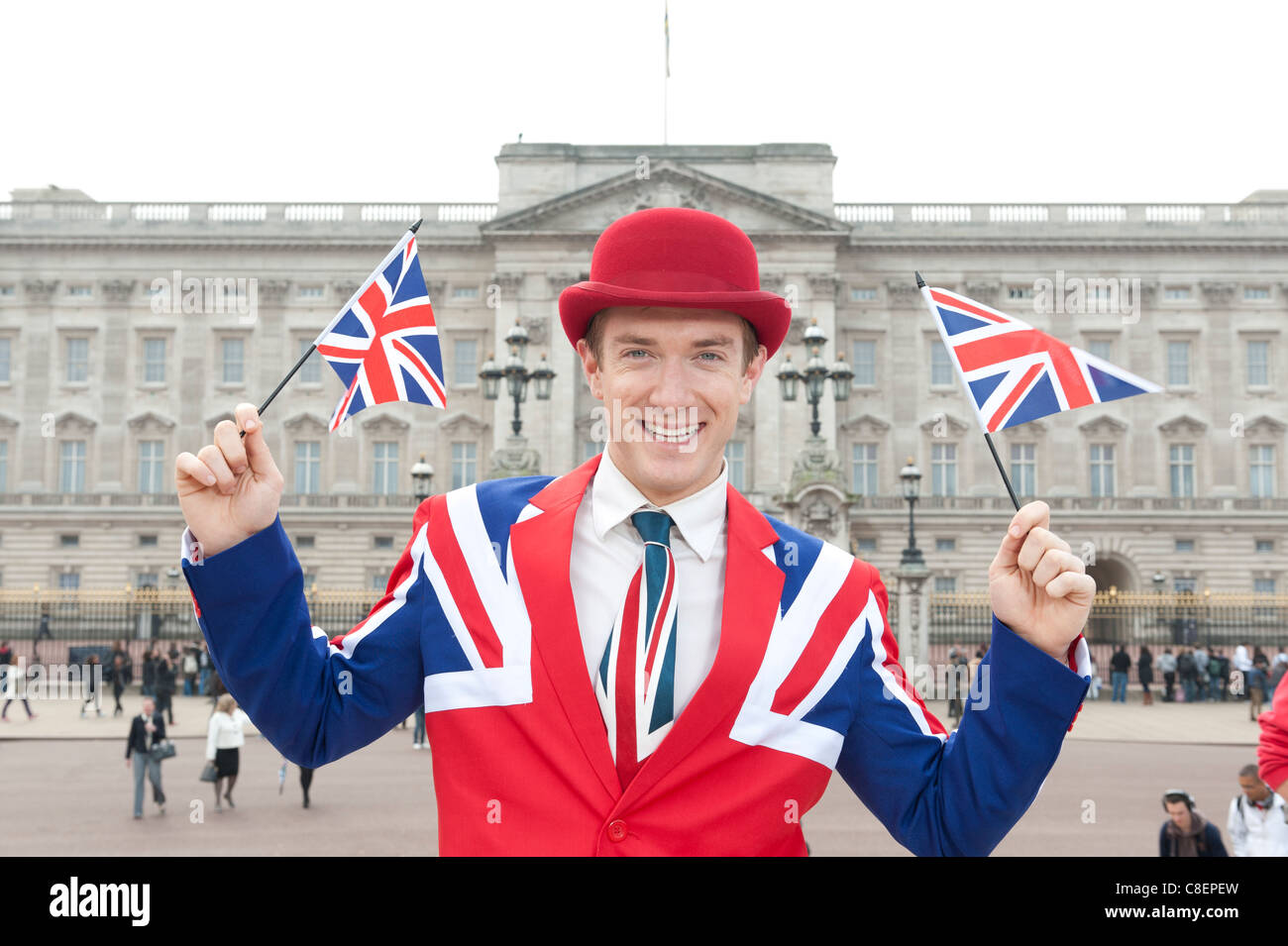 Homme portant patriotique union jack agitant des drapeaux de l'union tenue à Buckingham Palace, Londres Banque D'Images