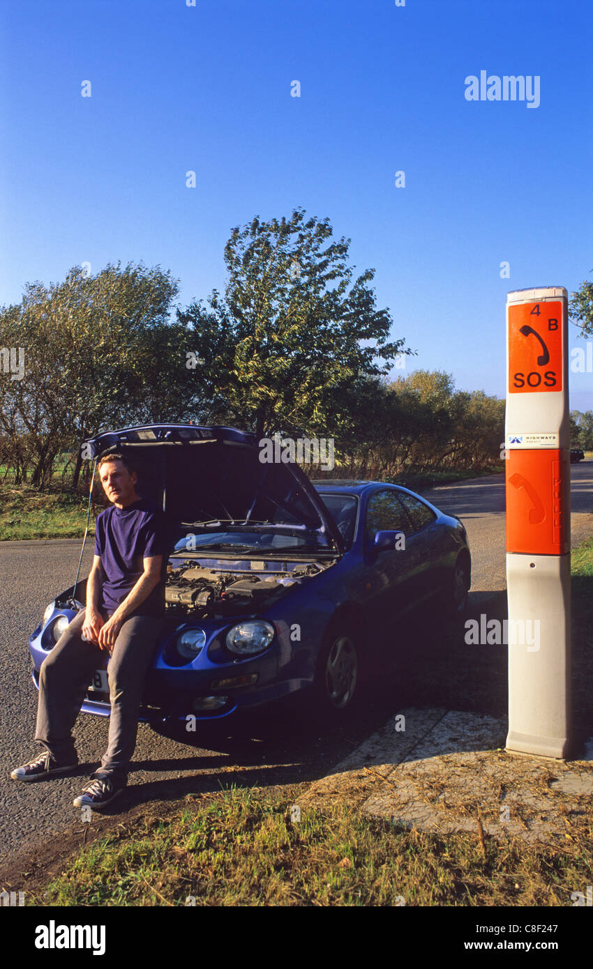 Man with broken down car en attente d'urgence sos panne téléphone au Royaume-Uni routière Banque D'Images