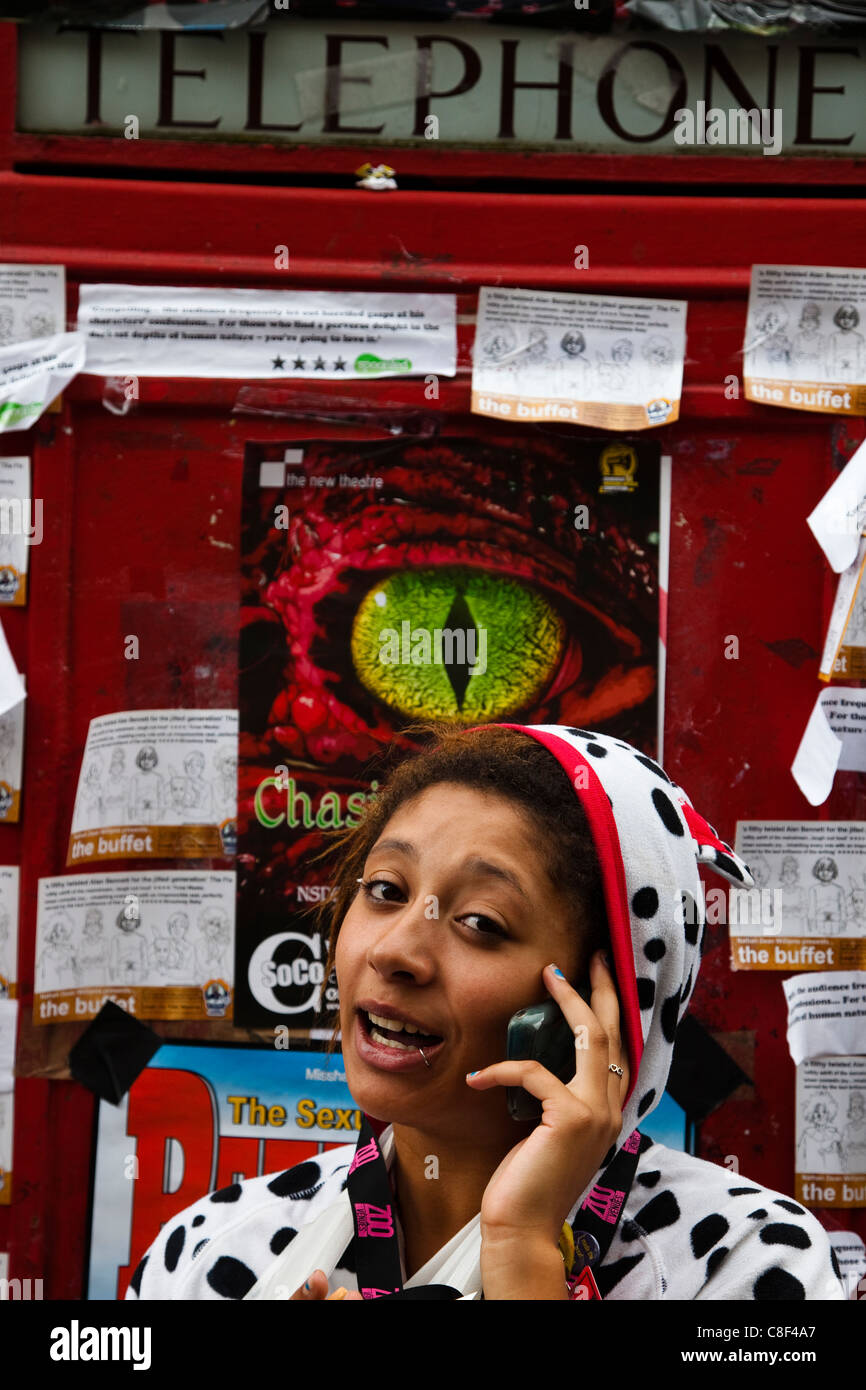 Jeune femme faire un appel sur son téléphone portable tout en se tenant à l'extérieur d'une cabine téléphonique, Édimbourg, Écosse, Banque D'Images