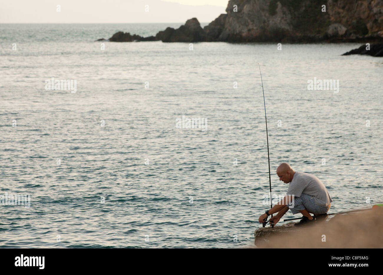 Un homme la pêche au mur du port. Talamone, Toscane, Italie. Banque D'Images