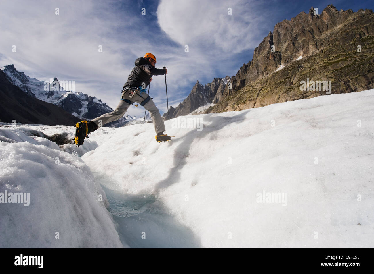 Climber jumping à travers une crevase stream sur Mer de Glace, Mont Blanc, Chamonix, Alpes, France Banque D'Images