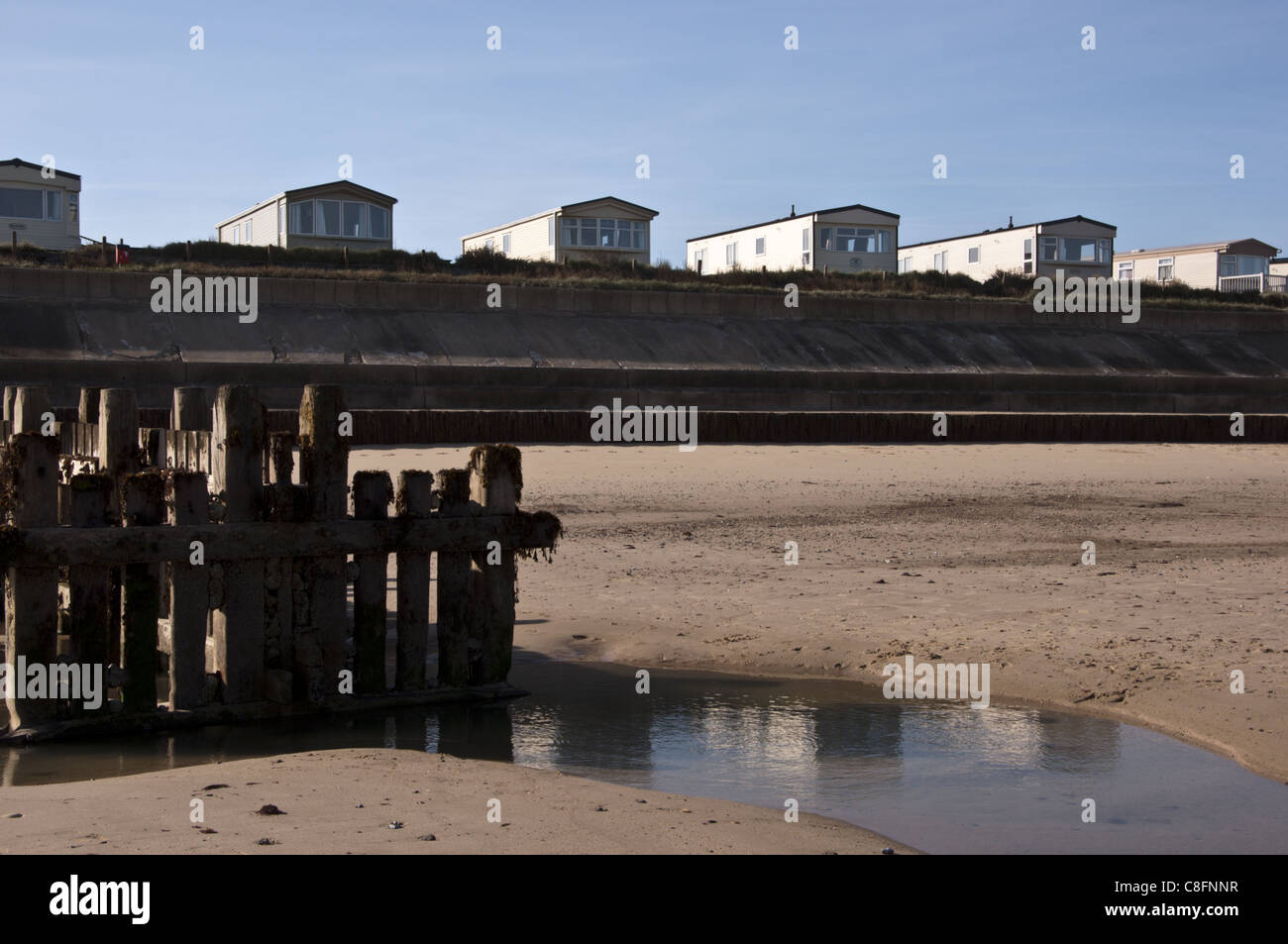 Caravane statique derrière la digue en béton de Bacton défenses Norfolk Banque D'Images