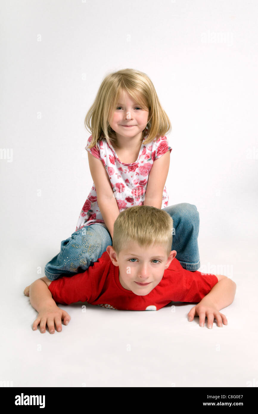 Deux des enfants de race blanche s'amusant avec 7 ans, assis sur le dessus de 8 ans frère Banque D'Images