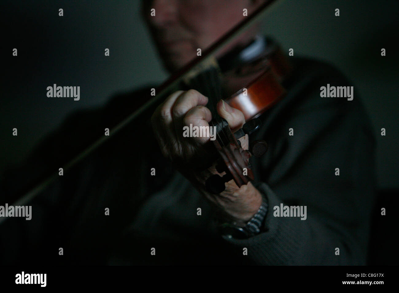 Un mâle adulte jouant la musique irlandaise au violon dans une salle sombre Banque D'Images