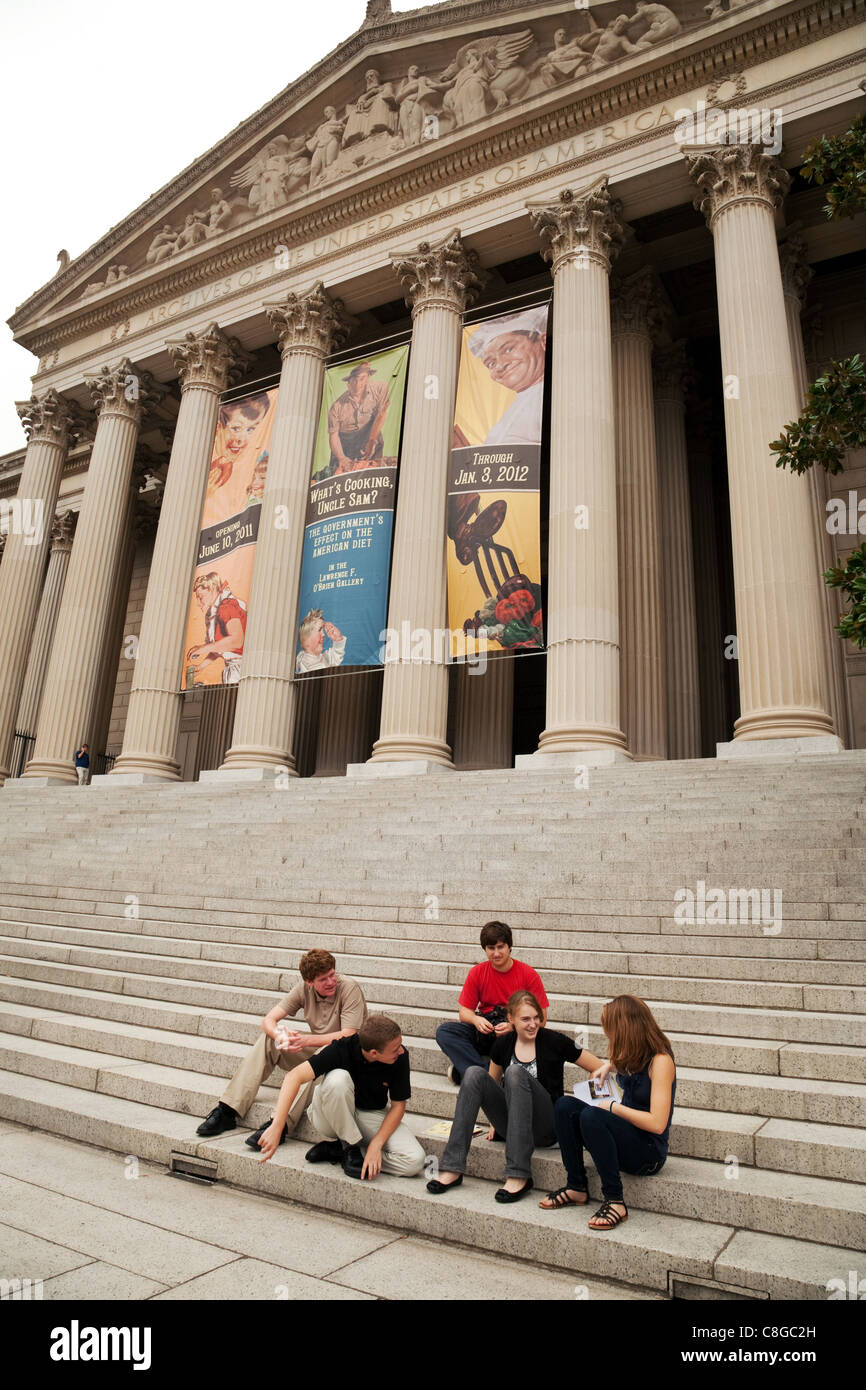 Les adolescents assis dehors l'avant de l'édifice des Archives nationales, Washington DC USA Banque D'Images