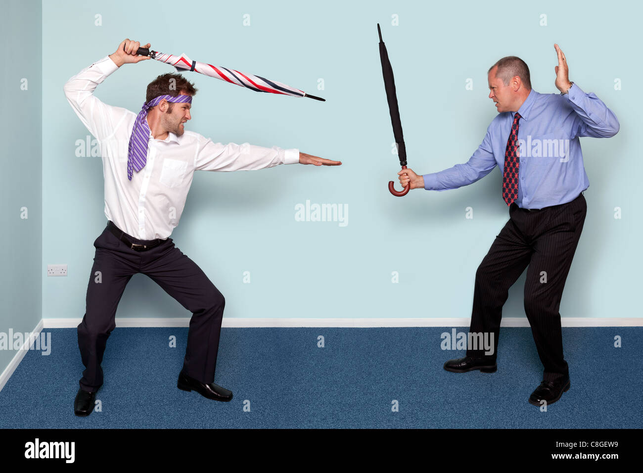 Photo de deux hommes d'avoir un combat à l'épée à l'aide de parapluies, bonne image pour véhiculer un conflit, rivalité ou de désaccord. Banque D'Images