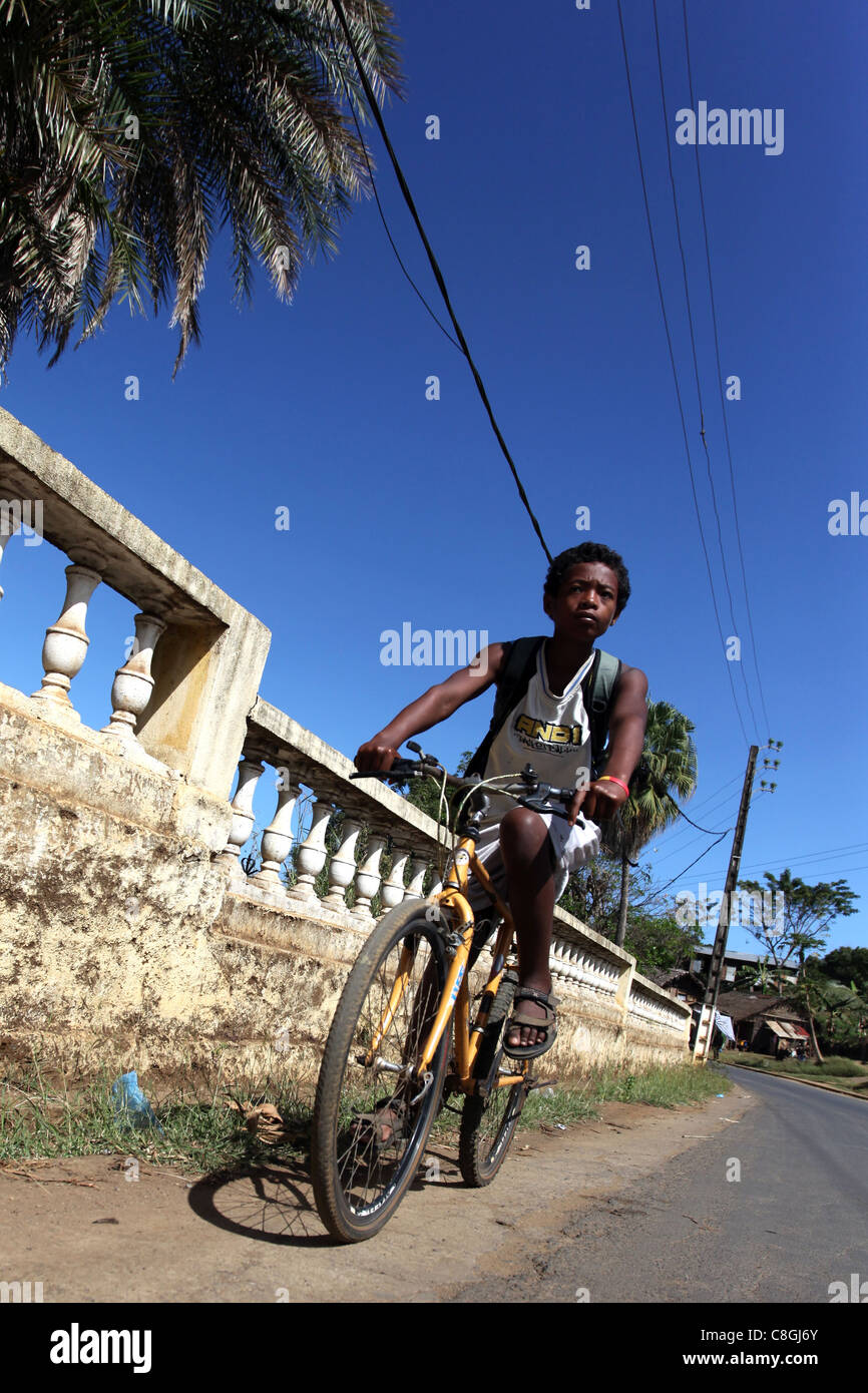Un garçon malgache équitation son vélo sur la route de Be Hell-Ville, Nosy Be, Nossi-bé, à Madagascar Banque D'Images