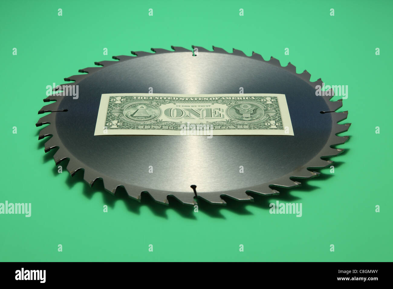 Billet de un dollar au milieu d'une lame de scie circulaire en métal. Fond vert vif, face arrière de billets Banque D'Images