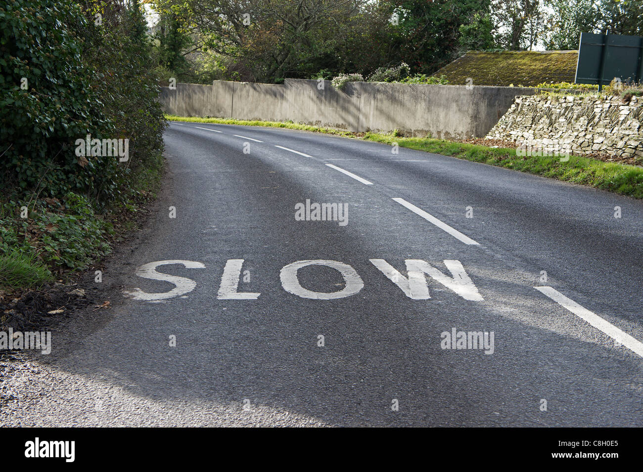 Un lent signe peint dans la route près d'un virage, uk Banque D'Images