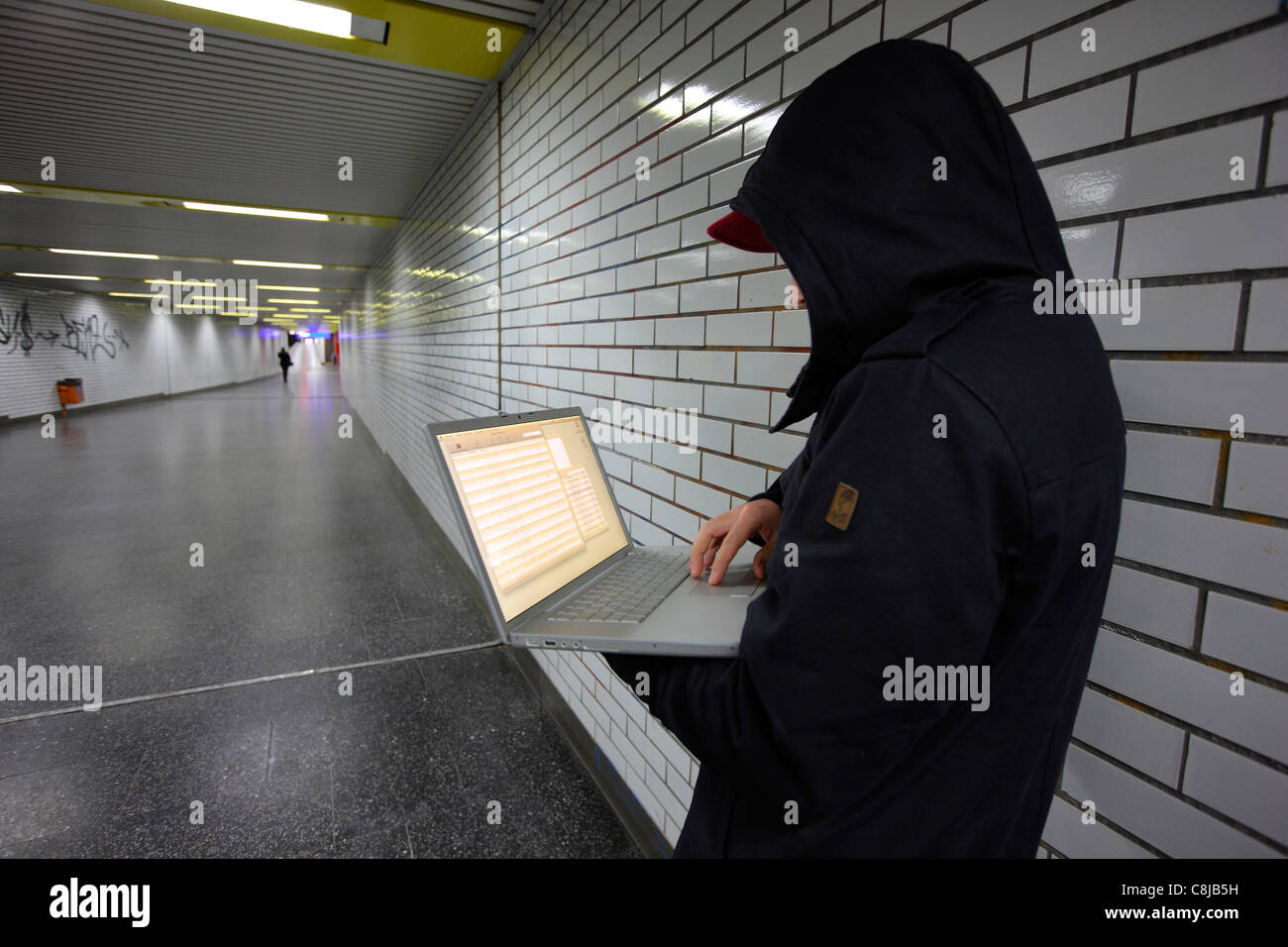 En informatique, hacker, siège de conspirateur avec un ordinateur portable, dans une station de métro. Photo symbole, de la criminalité sur Internet. Banque D'Images