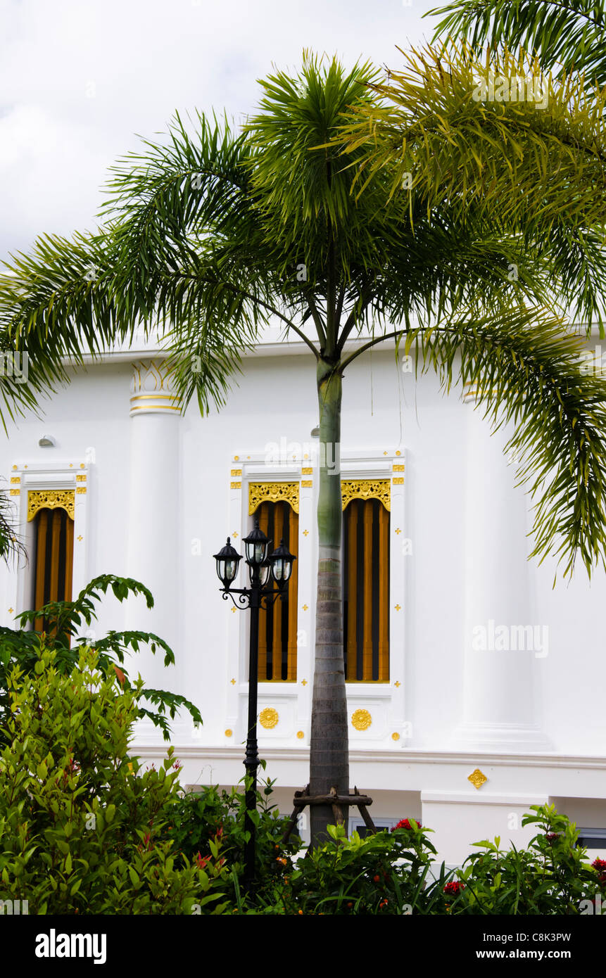 Bâtiment en stuc blanc avec des fenêtres décorées d'or derrière un palmier royal et noir lampadaire avec 3 lanternes Banque D'Images