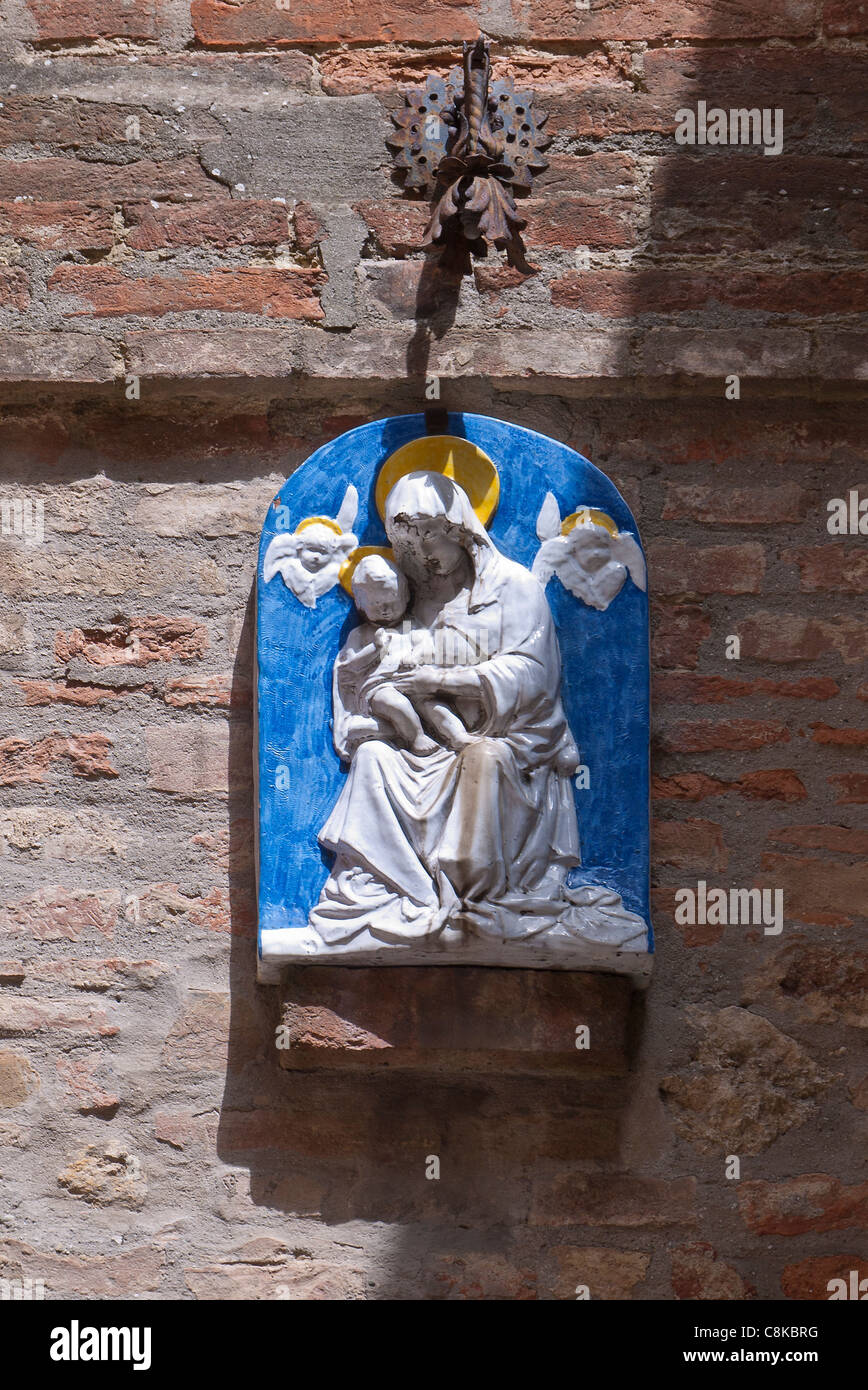 Un bas-relief plaque murale de la Vierge et l'enfant avec un fond bleu, chiffres blancs et jaunes halo, Chianciano Terme, Italie Banque D'Images