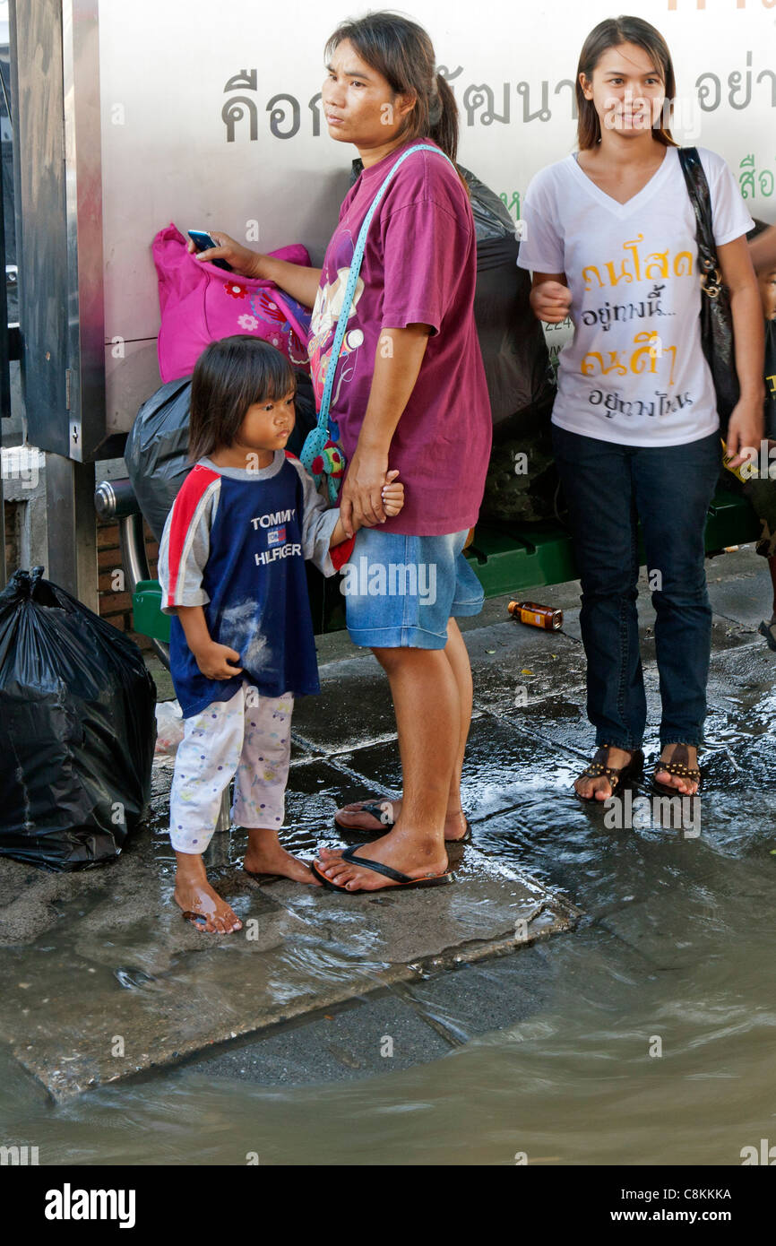 Mère et fille à l'arrêt de bus inondé, Bangkok, Thaïlande Banque D'Images