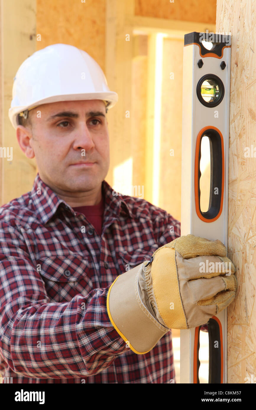 Vérification de la verticalité du mur builder avec un tube de niveau Banque D'Images