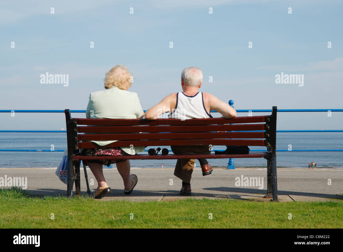 Couple de personnes âgées assis sur un banc face à la mer sur la journée ensoleillée à Seaton Carew près de Hartlepool, Angleterre, Royaume-Uni Banque D'Images