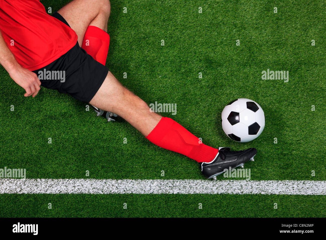 Photo prise à la verticale d'un joueur de soccer ou de football en coulissant pour sauver le ballon sur la ligne de touche Banque D'Images