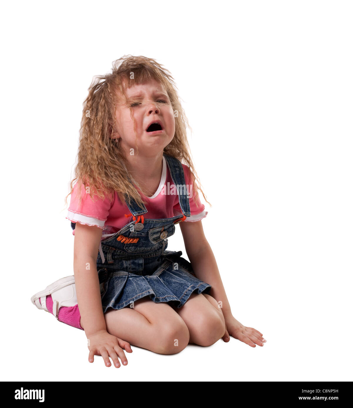 Enfant pleurant assis sur un chiffon blanc, jeans - isolé Banque D'Images