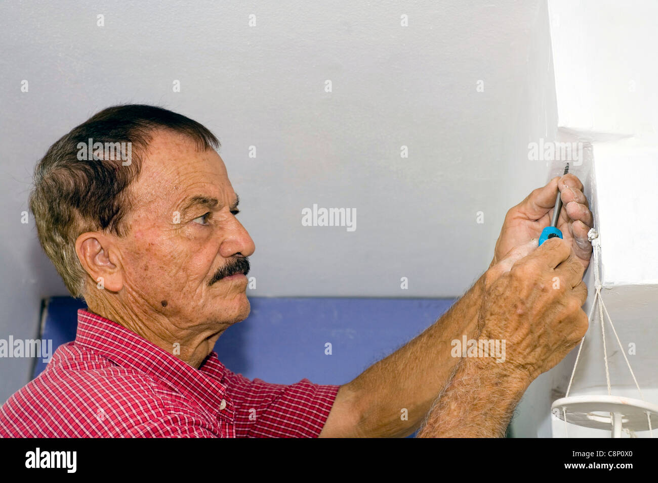 Un homme utilise un tournevis pour visser un petit creux dans un mur. Banque D'Images