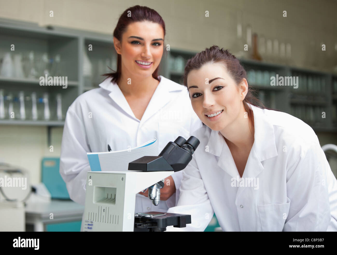 Les étudiants en science posant avec un microspcope Banque D'Images