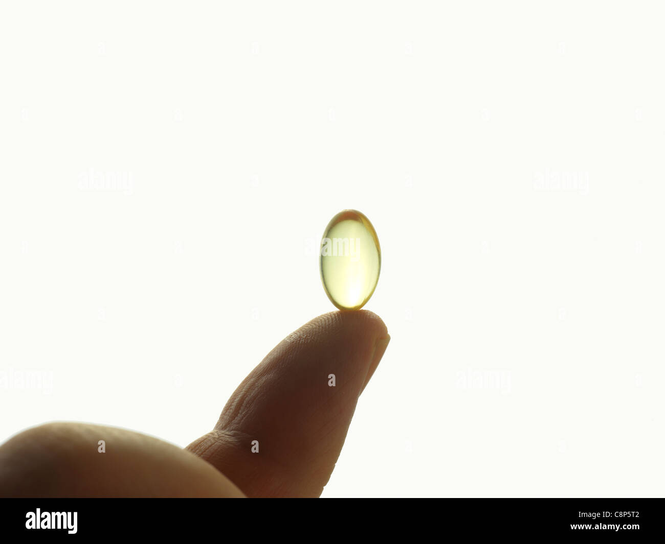 Une capsule remplie d'huile riche en vitamine E sur le bout d'un doigt Banque D'Images