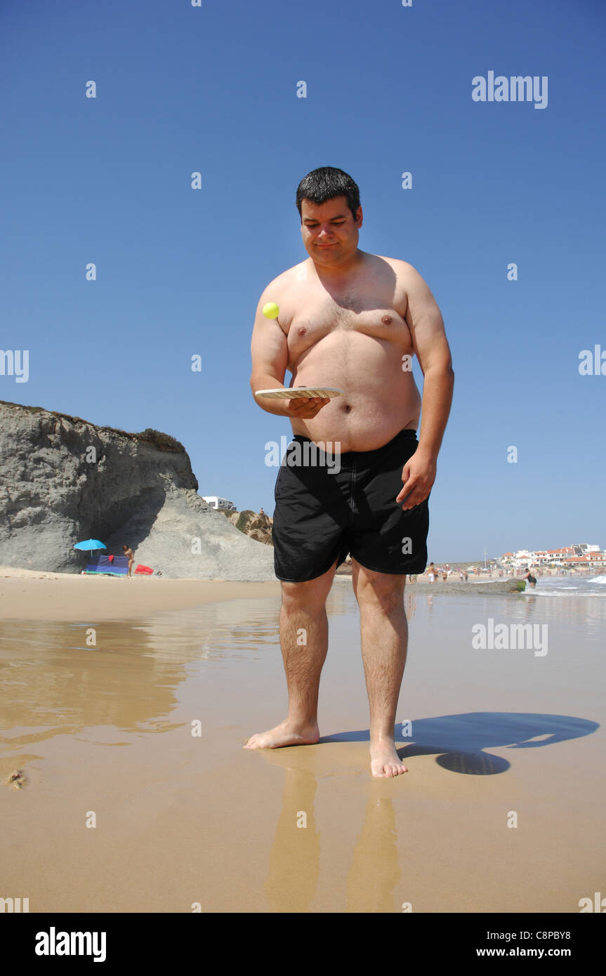 Un gros homme La pratique du beach tennis sur la plage Banque D'Images