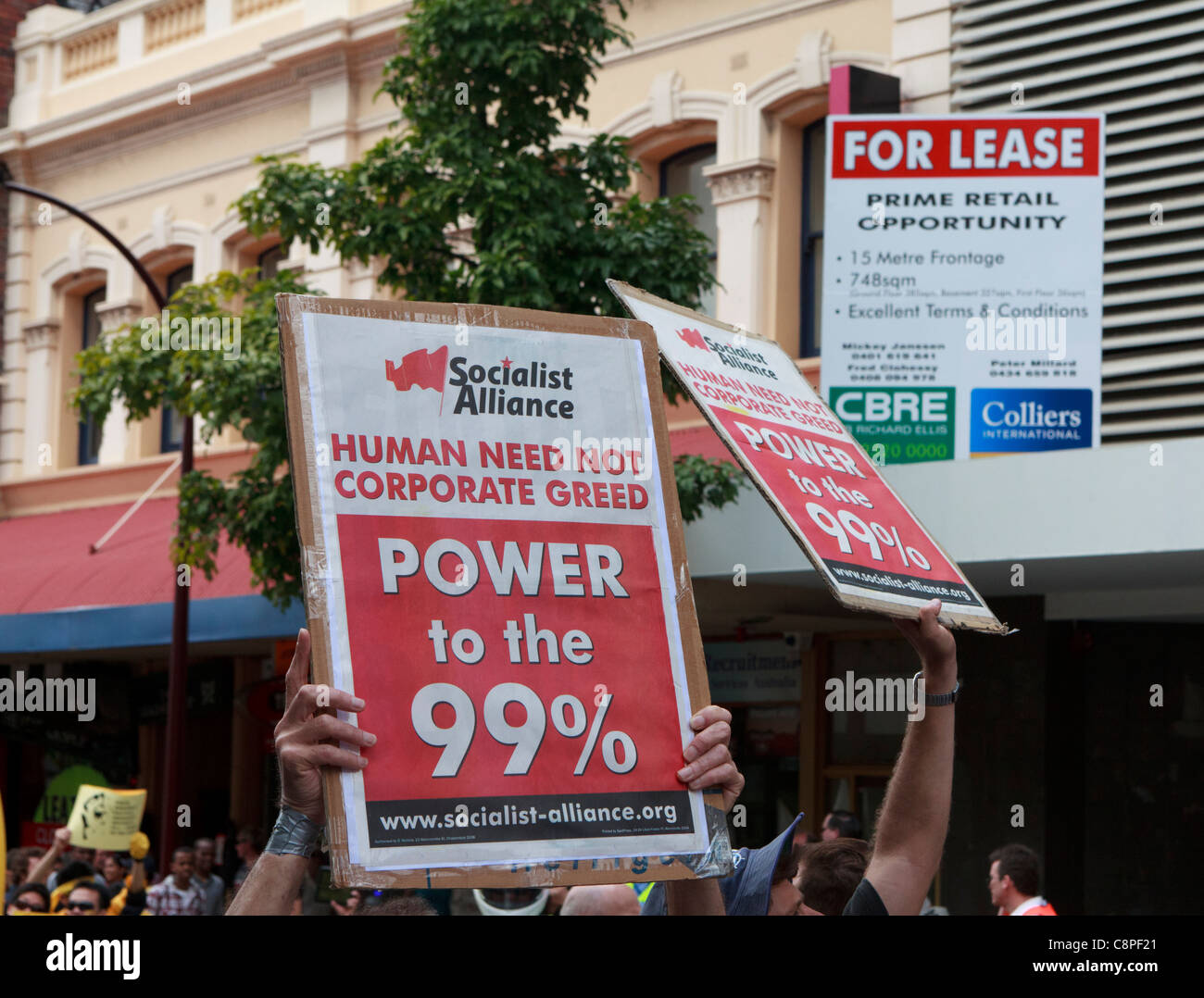 Les manifestants de l'Alliance socialiste hold 'Les droits de l'ont pas à la cupidité de l' & 'Pouvoir de la 99 %' des pancartes ci-dessous un "bail" pour signer. Banque D'Images