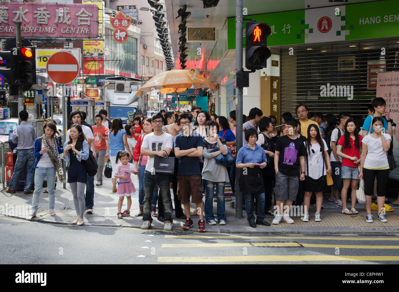 Un groupe de personnes en vue d'un passage pour piétons en attente de l'homme vert à Hong Kong Banque D'Images