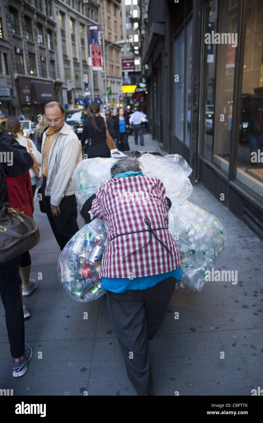 Femme plus âgée, la collecte des canettes d'aluminium dans la rue dans le quartier financier de New York nous reflète l'économie et la pauvreté croissante Banque D'Images