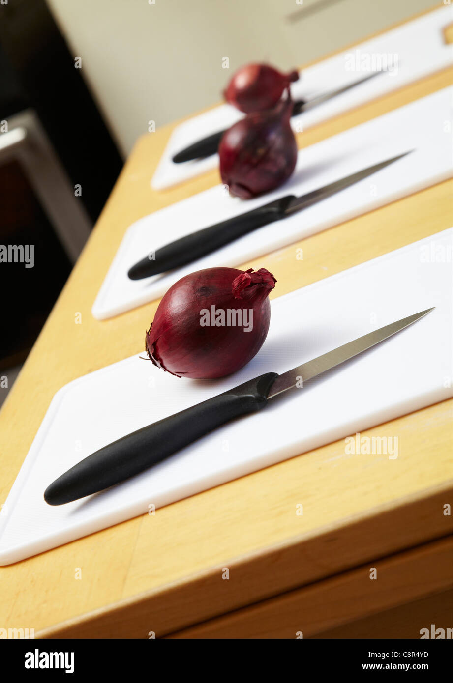Oignons rouges sur planche à découper avec couteau de cuisine. Prêt pour le broyage en cours de cuisine Banque D'Images