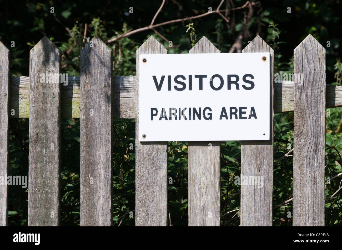 Un signe sur une clôture en bois lit Parking visiteurs Banque D'Images