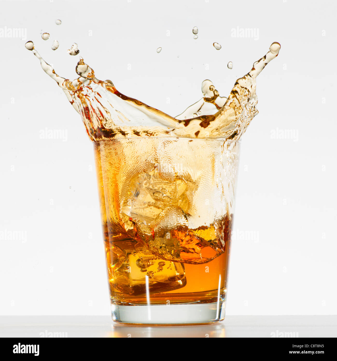 Studio shot of ice cubes splashing into glass of whiskey Banque D'Images