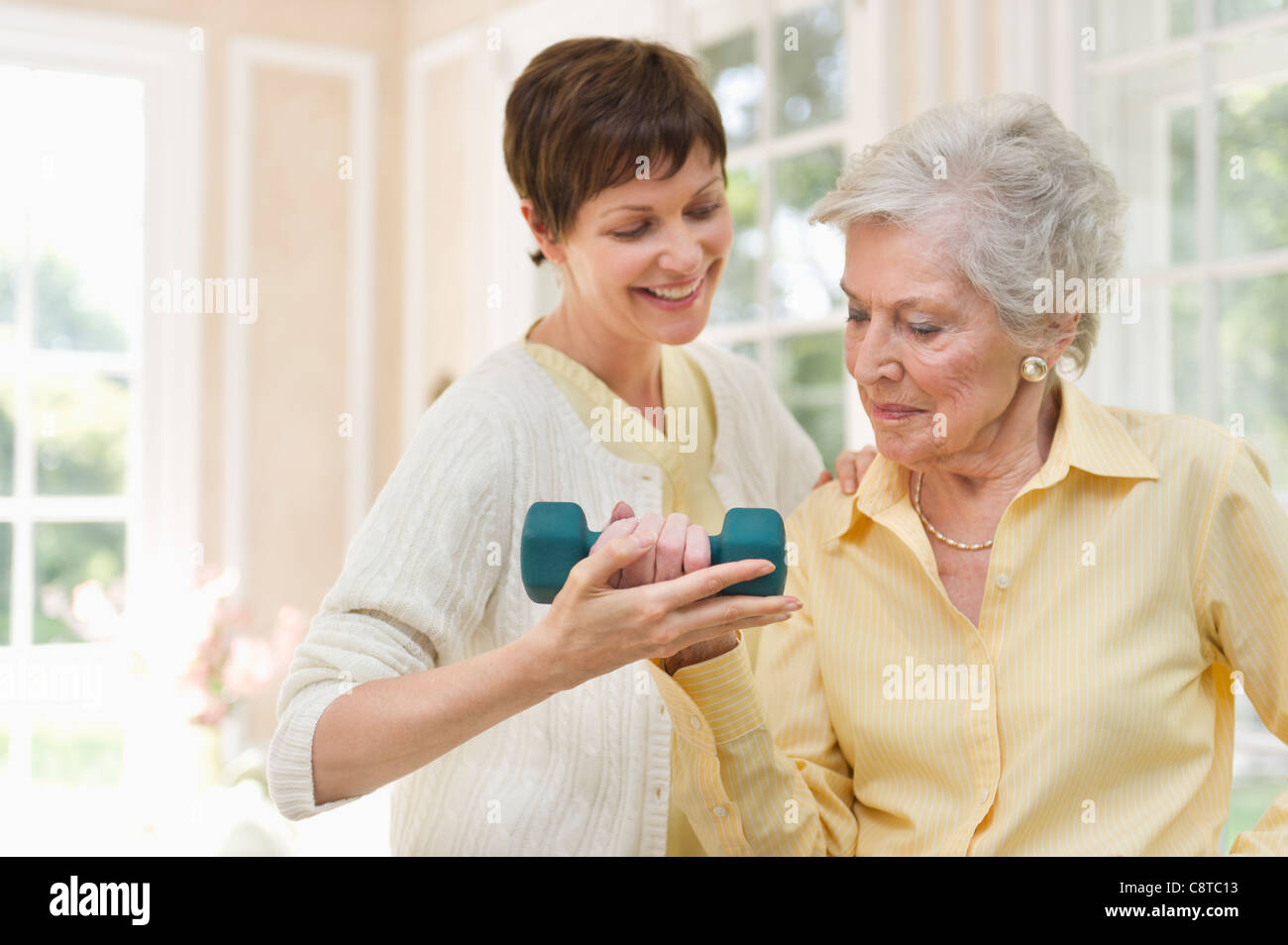 USA, New York State, Old Westbury, Senior woman lifting dumbbell, infirmière l'aider Banque D'Images
