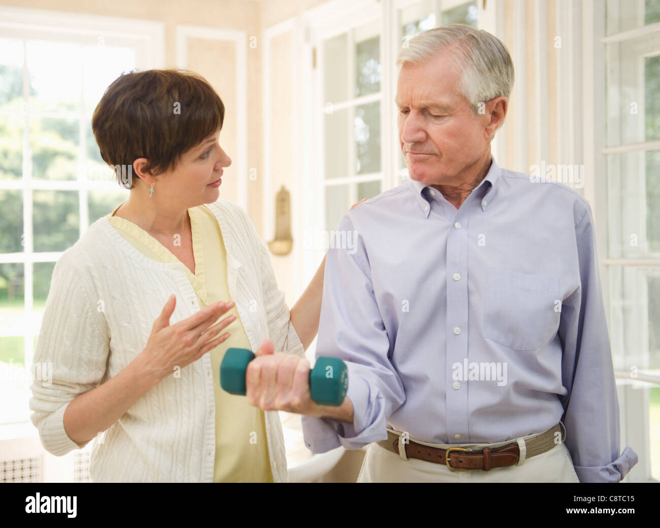 USA, New York State, Old Westbury, Senior man lifting dumbbell, infirmière aide à lui Banque D'Images