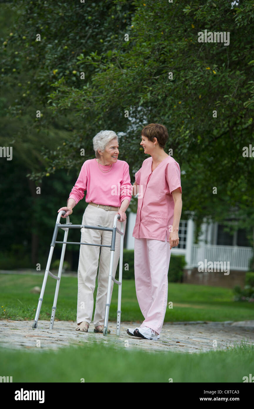 USA, New York State, Old Westbury, Senior woman walking with walker avec l'aide de l'assistant de soins infirmiers Banque D'Images