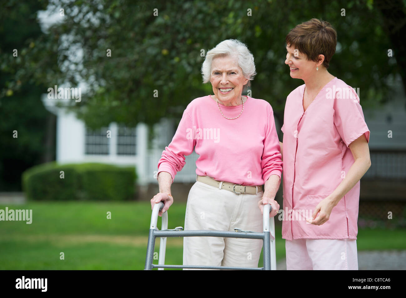 USA, New York State, Old Westbury, Senior woman walking with walker avec l'aide de l'assistant de soins infirmiers Banque D'Images