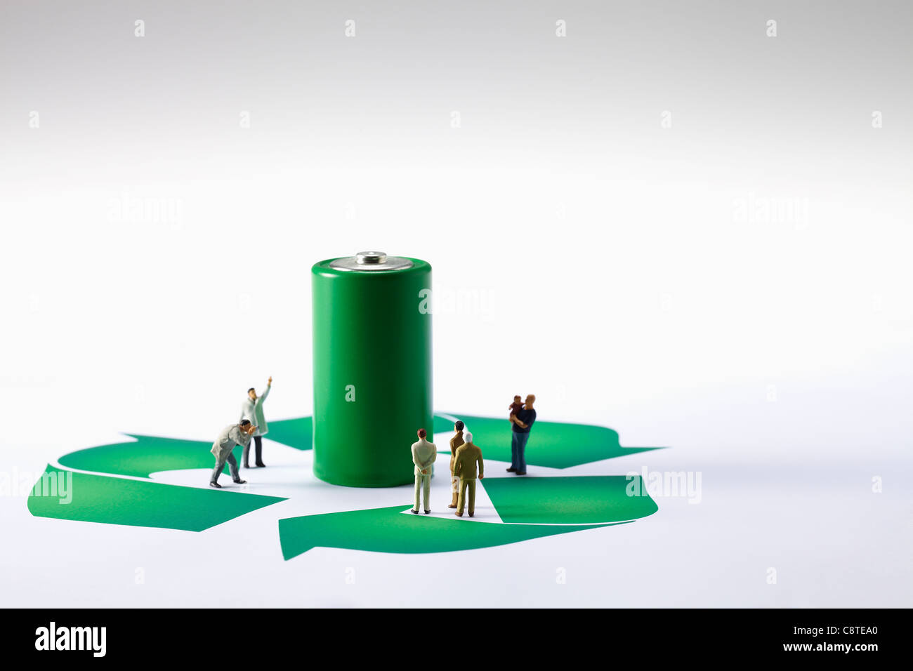 Batterie verte avec des petites figurines et symbole de recyclage sur fond blanc Banque D'Images