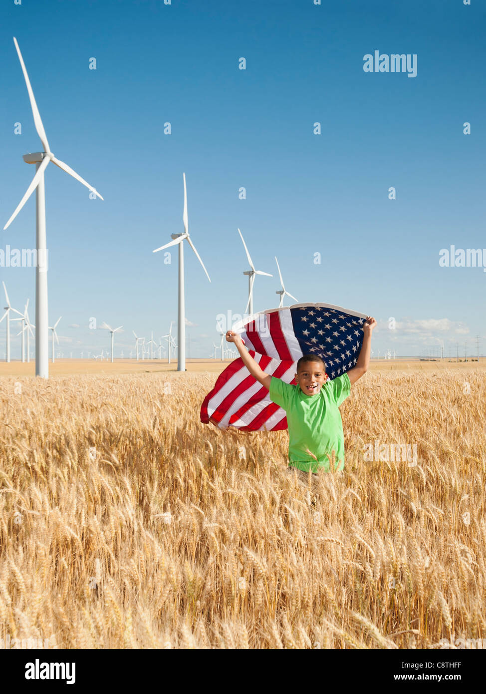 USA, Ohio, Wasco, enfant volant drapeau américain dans le champ de blé aux éoliennes en arrière-plan Banque D'Images