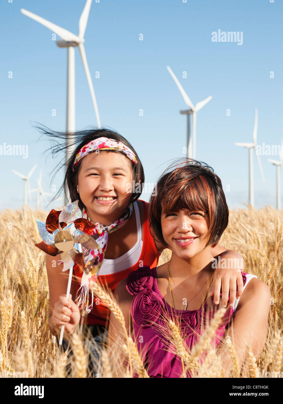 USA, Ohio, Wasco, Portrait de deux jeunes filles debout dans le champ de blé, les éoliennes en arrière-plan Banque D'Images